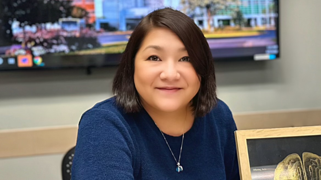 Woman sits smiling at desk