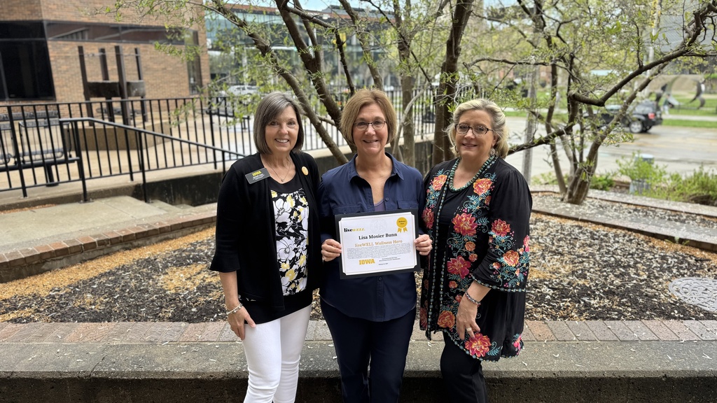 Three women standing outside of the Lindquist Center displaying award